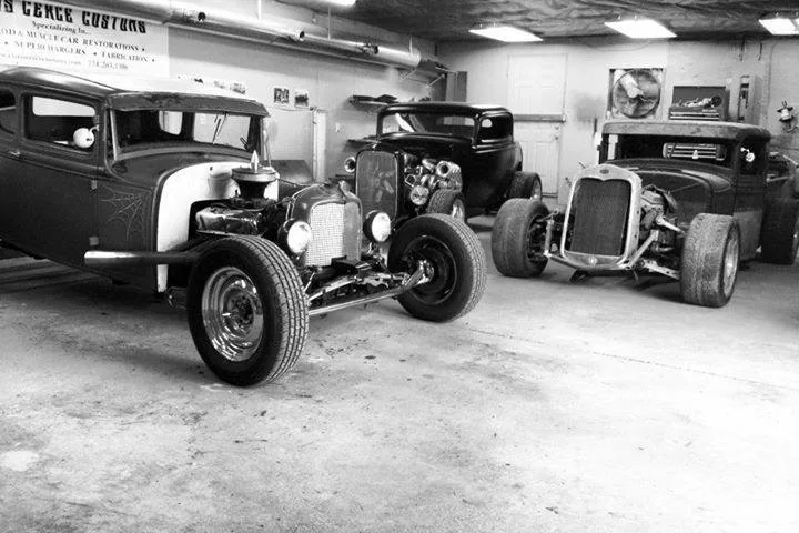 Archival workshop view of three traditional hot rods