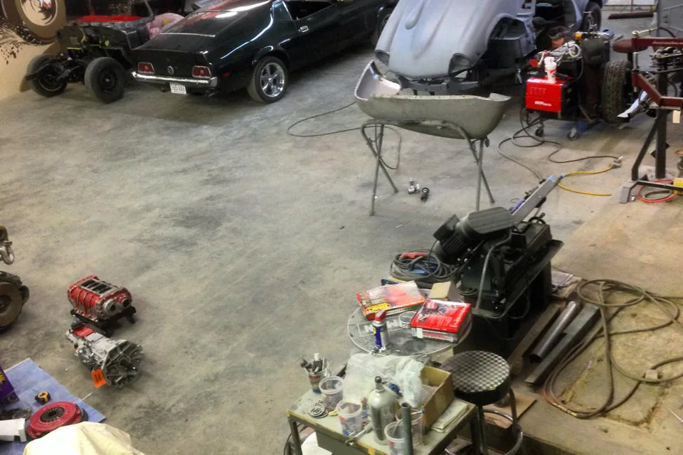 Archival overhead view of vehicle projects and equipment inside an earlier workshop