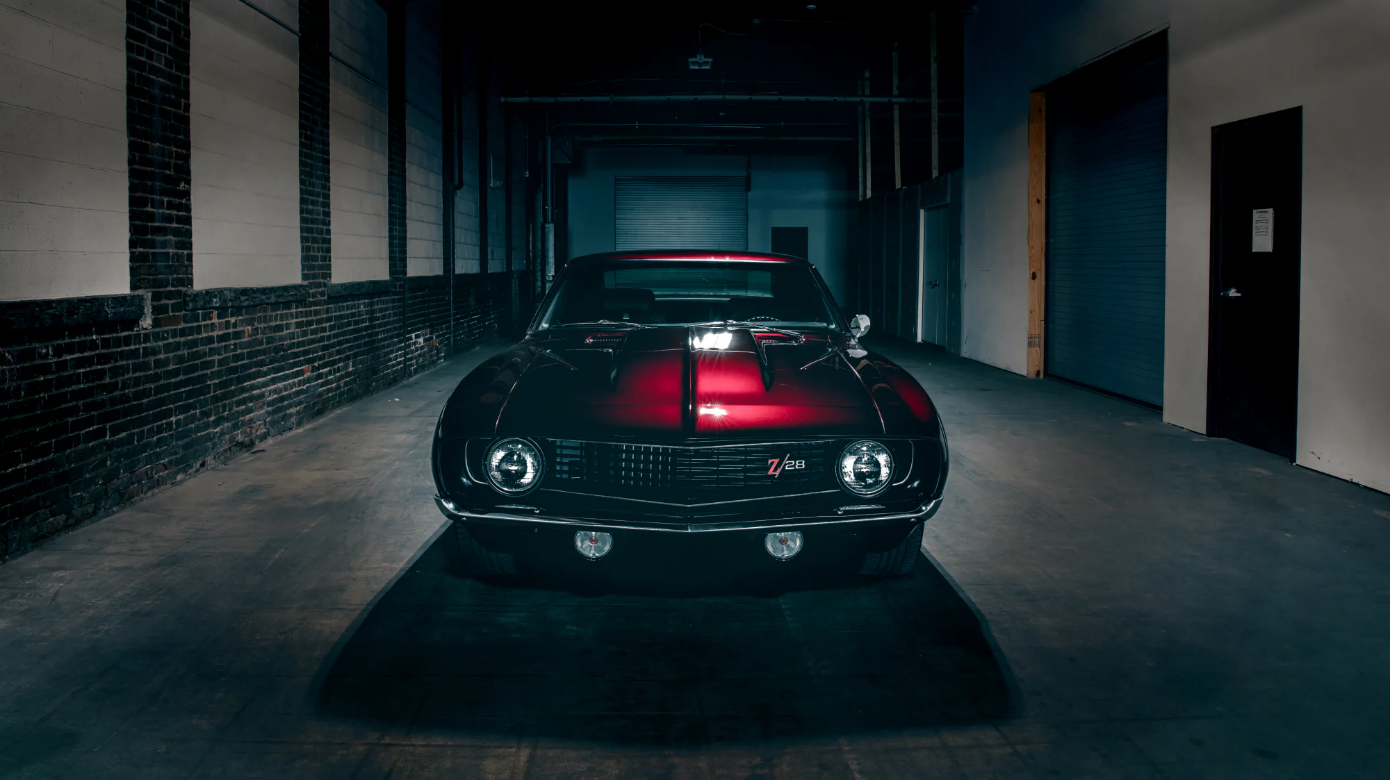 Candy red Chevrolet Camaro photographed in a dark industrial garage