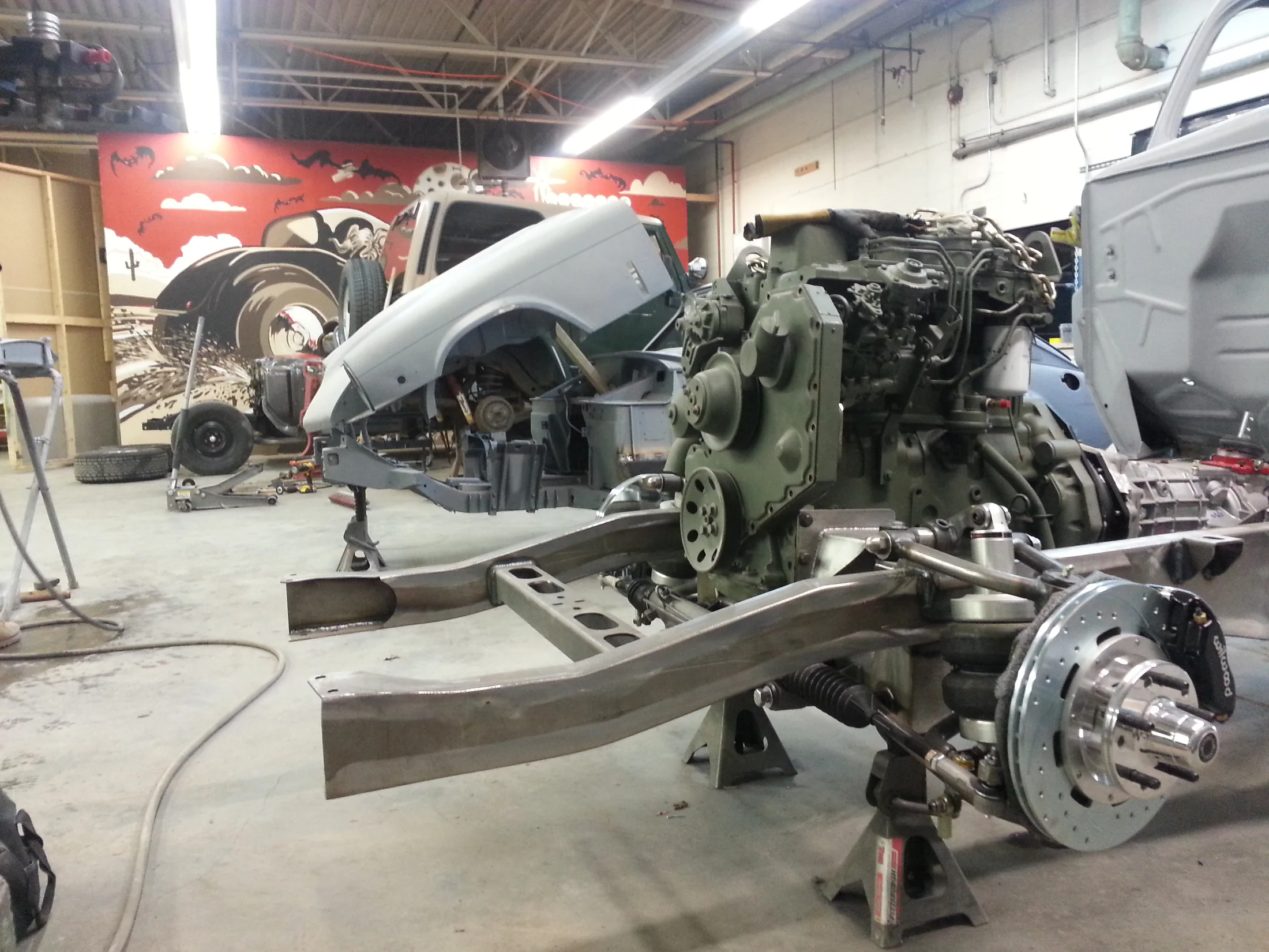 Bare truck frame and suspension components during assembly inside a workshop
