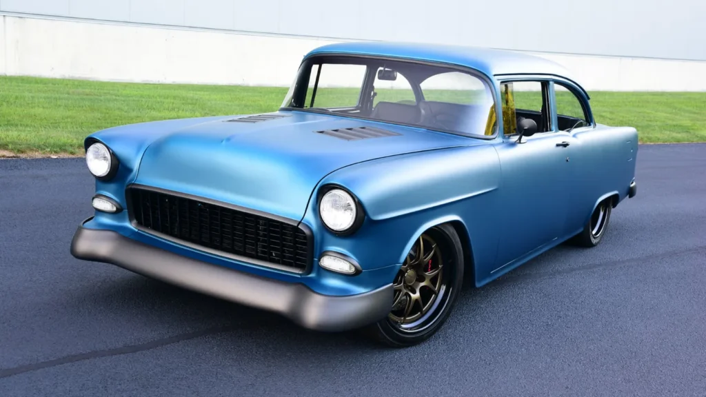 Blue 1955 Chevrolet 150 photographed outside a white industrial building