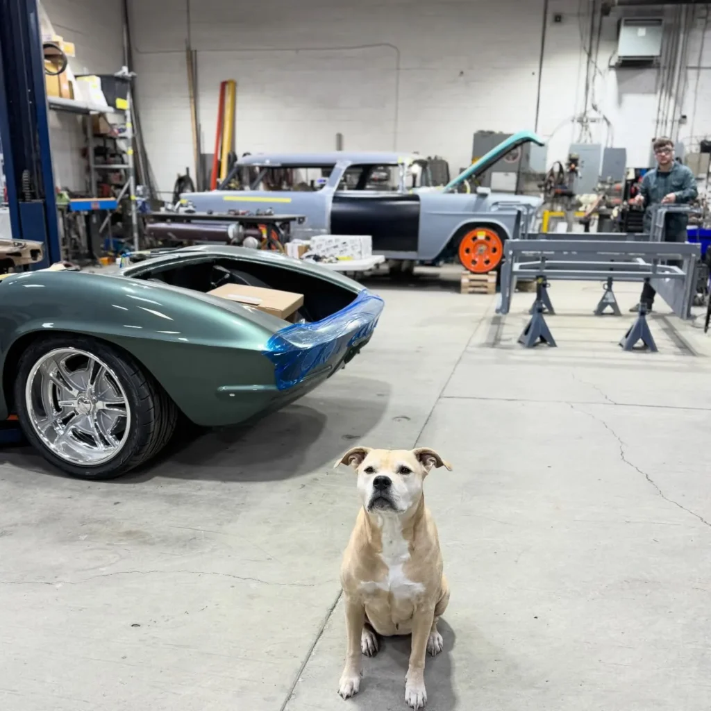 Layla sitting in the workshop beside the green Corvette